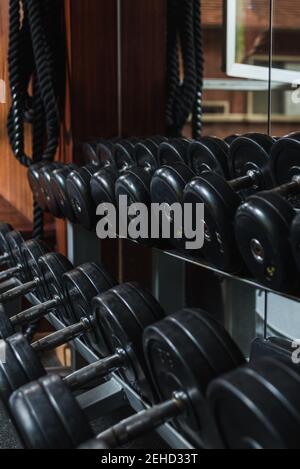 Haltères noires lourdes avec barres métalliques et plaques réfléchissantes miroir dans la salle de gym en journée Banque D'Images