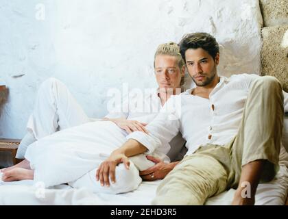 Deux hommes assis sur le lit qui regardent loin Banque D'Images