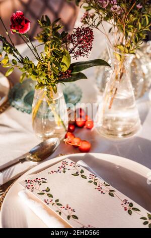 Table de fête avec verres en cristal et couverts serviette sur l'assiette près d'un bouquet de fleurs fraîches pour le mariage et la carte de menu Banque D'Images