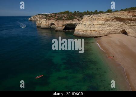 Vue spectaculaire de la vieille ville sur une rive sablonneuse contre la mer sans fin avec horizon sous ciel bleu ciel nuageux dedans Carvoeiro Portugal Banque D'Images