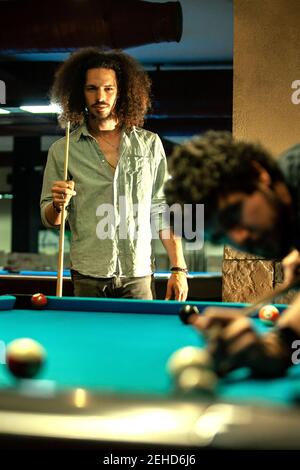 Homme d'éthique sérieux avec CUE en compétition avec le joueur frapper la boule de billard Banque D'Images