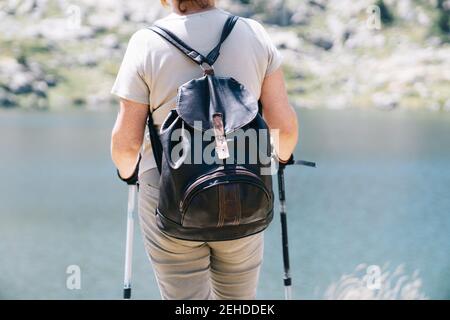 Vue arrière une randonneur anonyme debout avec des bâtons de marche côte de la rivière stony dans les Pyrénées catalanes par beau temps d'été Banque D'Images