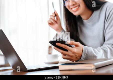 femme utilisant un téléphone portable lorsqu'elle travaille à la maison. Concept de travail femme d'affaires. Banque D'Images