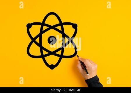 Main mâle représentant une icône d'atome sur fond jaune. Concept de la science et de la technologie. Banque D'Images