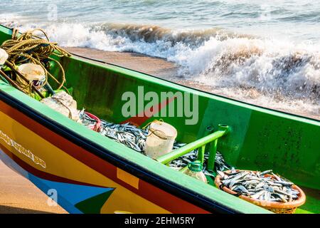 Bateau de pêche avec filet de pêche rempli de poissons et d'océan vagues en arrière-plan Banque D'Images