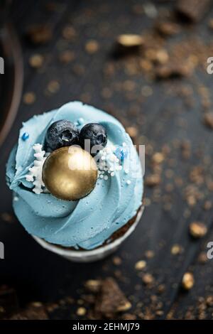 Plusieurs muffins ou cupcakes à la crème de forme bleue et au blueberrieson à table noire sur fond sombre. Espace de copie de style rustique. Banque D'Images