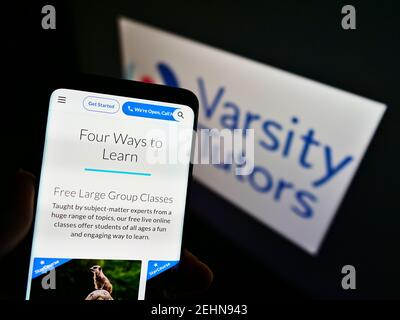 Personne tenant un téléphone mobile avec le site Web de la plate-forme d'apprentissage américaine Varsity tuteurs sur l'écran devant le logo. Concentrez-vous sur le centre de l'écran du smartphone. Banque D'Images