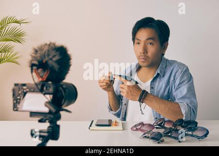 Frontal asiatique vlogger ou Blogger dans Jean chemises examen mode verres par enregistrement vidéo. Freelance Online Streaming avec le client via social Med Banque D'Images