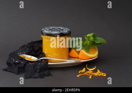 un bocal à confiture d'orange décoré de menthe et d'orange coupes sur fond noir Banque D'Images