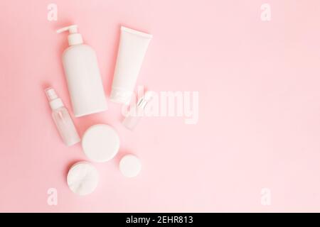 Pots blancs de cosmétiques sur fond rose pastel. Accessoires de bain. Concept de soins du visage et du corps. Espace de copie, plan de travail Banque D'Images