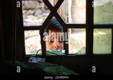 Budgam, Inde. 19 février 2021. Un enfant regardant la maison endommagée par une fenêtre, la maison waa endommagée lors d'une rencontre entre les meuniers et les forces dans la région de beerwah, dans le district de Budgam, le 19-02-2021. (Photo de Muhammad Manan/Pacific Press) crédit: Pacific Press Media production Corp./Alay Live News Banque D'Images