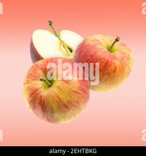 Voler rouge frais entier et couper les pommes sur fond rose. Banque D'Images