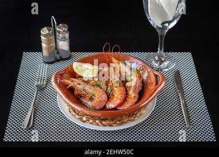 Crevettes cuites dans un bol en argile, couverts sur les côtés et un verre d'eau. Composition d'un repas prêt à être mangé. Banque D'Images