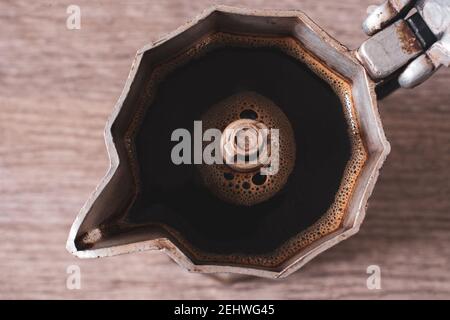 Gros plan d'une marmite ouverte avec du café chaud sur une table en bois. Banque D'Images