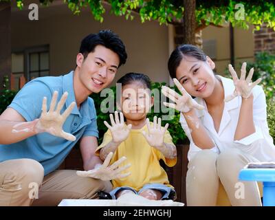 Une famille heureuse de trois personnes qui font de la poterie ensemble en plein air souriant Banque D'Images