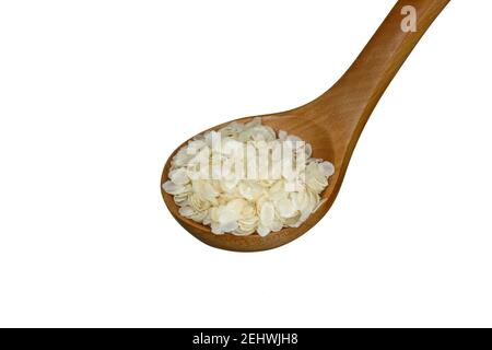 flocons de riz aplatis dans une cuillère en bois isolée sur blanc. Banque D'Images