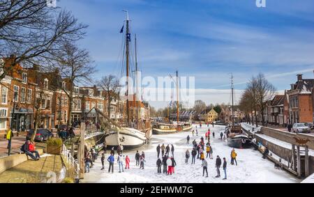 Des gens sur la glace dans le port historique de Dokkum, pays-Bas Banque D'Images