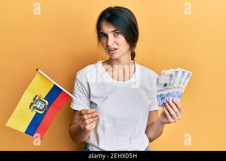 La jeune femme caucasienne détient le drapeau colombien et les billets colombiens pesos expression sans indice et confuse. Notion de doute. Banque D'Images