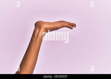 Bras et main de la femme d'âge moyen noire sur fond rose isolé avec paume plate présentant le produit, offre et donnant geste, espace de copie vierge Banque D'Images