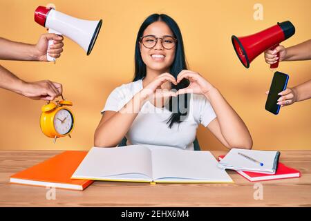 Jeune belle fille asiatique stuying pour l'université se stressant en souriant en amour faisant le symbole de coeur de forme avec les mains. Concept romantique. Banque D'Images