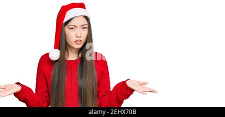 Jeune femme chinoise portant un chapeau de noël sans indice et confondu avec les bras ouverts, pas de concept d'idée. Banque D'Images