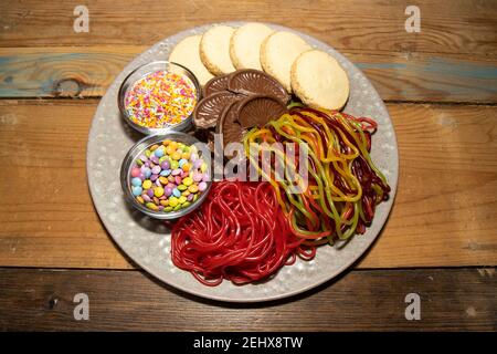 Une délicieuse assiette de bonbons, biscuits et chocolats sur une table en bois Banque D'Images