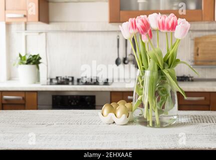 Œufs peints en or de Pâques et bouquet printanier dans la cuisine. Intérieur. Banque D'Images