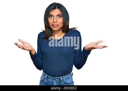 Jeune femme transsexuelle transgenre latine portant des vêtements décontractés expression sans indice et confuse avec les bras et les mains soulevées. Doute concept. Banque D'Images