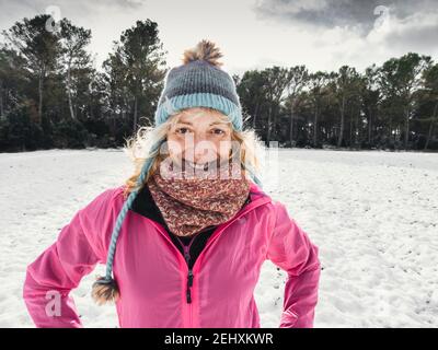 Bonne jeune femme caucasienne avec un chapeau et un imperméable rose profitant de la neige en plein air en hiver. Navarre, Espagne, Europe. Banque D'Images