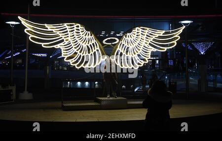 Une jeune fille pose devant une paire d'ailes d'ange illuminées à Chavasse Park, Liverpool, Angleterre Banque D'Images