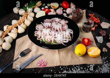 Poulpe de bébé crue dans une assiette noire. Fruits de mer biologiques. Vue de dessus. Banque D'Images