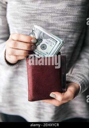 Dans les mains des femmes se trouve le portefeuille en cuir marron avec une Wad de cent dollars. Offre commerciale. Belle manucure Banque D'Images
