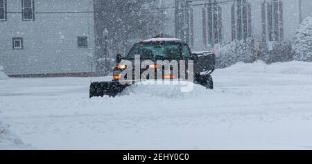 Un contractuellement privé laboure la neige dans un parking pour les entreprises locales. Banque D'Images