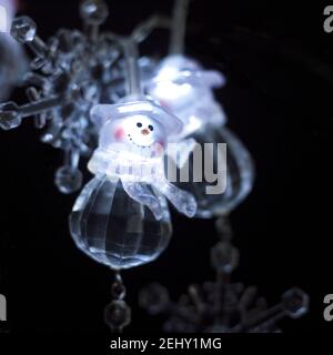 Photo macro d'une jolie guirlande de lumières de Noël en forme de bonhomme de neige sur fond noir Banque D'Images