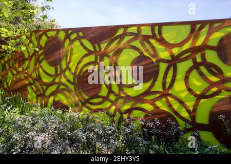 Un jardin urbain moderne et contemporain avec des panneaux de clôture en acier corten Et couleur verte - ciel bleu au printemps Angleterre GB Frontières florales du Royaume-Uni Banque D'Images