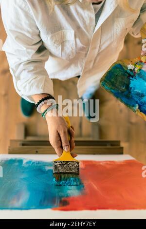 Femme peinture art abstrait sur toile à chevalet. Vue de dessus. Concentrez-vous sur le pinceau dans la main féminine Banque D'Images