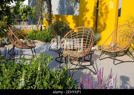 Jardin moderne design méditerranéen climat jardin moderne pierre grise pavé patio coin salon table en rotin et chaises en rotin sur une terrasse Hampton Banque D'Images