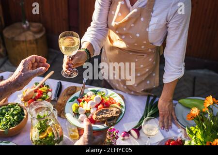 Dégustez du vin blanc et de la salade de légumes lors de la fête dans le jardin. Une femme sert de la nourriture et des boissons à une autre personne lors d'un événement de célébration en plein air Banque D'Images