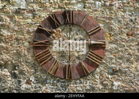 Une horloge en métal antique avec des chiffres romains sur une pierre Mur Banque D'Images