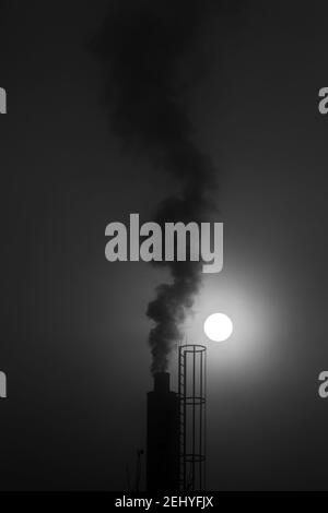 Noir et blanc Photographie d'un Chimney avec fumée à venir Hors de lui et pleine lune en arrière-plan Banque D'Images