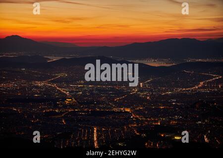 Coucher de soleil tard avant la nuit sur Athènes de Grèce avec le ville illuminée en premier plan et les montagnes et le mer en arrière-plan Banque D'Images