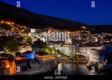 Photographie nocturne d'une ville illuminée de Dubrovnik avec son mur, la montagne et le ciel bleu foncé Banque D'Images