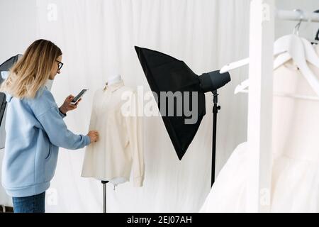 Technologie AR VR dans l'industrie de la mode. Une femme de créateur a mis des vêtements sur un mannequin par téléphone portable pour une application de réalité augmentée. Solutions AR VR Banque D'Images