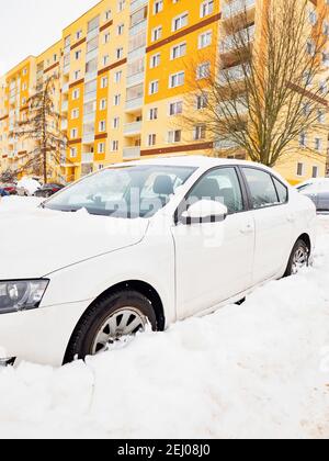 Voiture perdue sous une énorme neige et une maison de résidence jaune orange Dans une rue en hiver Banque D'Images
