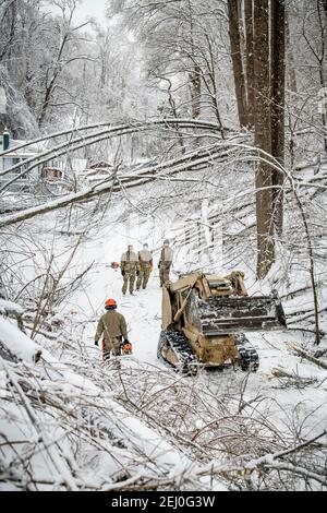 Ceredo, États-Unis. 19 février 2021. Les soldats américains de la Garde nationale de Virginie-Occidentale dépovent les débris d'une tempête d'hiver au large d'une route le 19 février 2021 à Ceredo, dans le comté de Wayne, en Virginie-Occidentale. Plus tôt dans la semaine, un grand système de tempête d'hiver a laissé plus de 90,000 Virginie occidentale sans électricité dans toute la région, faulant les arbres et rendant les routes éloignées impraticables. Credit: Planetpix/Alamy Live News Banque D'Images