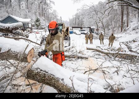 Ceredo, États-Unis. 19 février 2021. Les soldats américains de la Garde nationale de Virginie-Occidentale dépovent les débris d'une tempête d'hiver au large d'une route le 19 février 2021 à Ceredo, dans le comté de Wayne, en Virginie-Occidentale. Plus tôt dans la semaine, un grand système de tempête d'hiver a laissé plus de 90,000 Virginie occidentale sans électricité dans toute la région, faulant les arbres et rendant les routes éloignées impraticables. Credit: Planetpix/Alamy Live News Banque D'Images