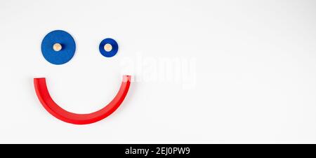 Jouet sourire visage , personnage de smiley de dessin animé, petit clown géométrique jouet sur fond blanc. Vue de dessus Banque D'Images