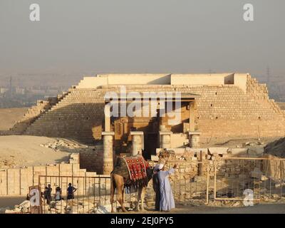 Giza, Égypte, 20 novembre 2018. 2 hommes avec un chameau sont photographiés dans la zone de la pyramide de pas de Djoser (Zoser) et du temple mortuaire. Banque D'Images