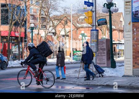 Ottawa (Ontario), Canada - le 6 février 2021 : dans le village Somerset, les gens marchent et font du vélo à l'intersection des rues Somerset et Bank. Certains de t Banque D'Images