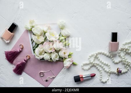 Luxe romantique fond: Fleurs blanches, collier de perles, parfum, carte de voeux sur blanc.accessoires et fleurs. Achat en ligne ou concept de rencontres Banque D'Images
